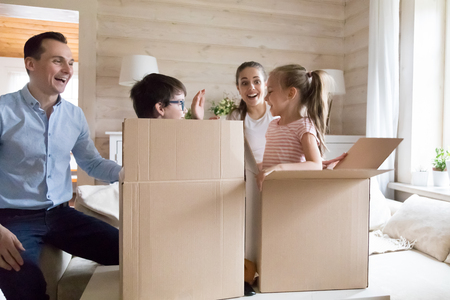 Family with children excited moving new house playing unpacking boxes. Happy mother and father having fun with kids at new home. Moving day, mortgage, loan, credit, relocation concept. New life stageの写真素材