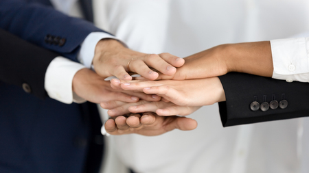 Diverse business people group in suits join hands in stack pile supporting team unity, corporate strength union, employees integrity, help in partnership and help in teamwork concept, close up viewの写真素材
