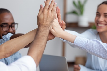 Close up view happy smiling diverse business team giving high five celebrating win, goal...