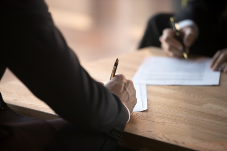 Close up of male workers sign contract closing successful deal in office, businessmen put signature on agreement, start collaboration or partnership, business partners agree on cooperation at meetingの写真素材