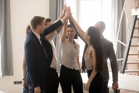 Excited multicultural business people group give high five as dream team unity concept, happy...