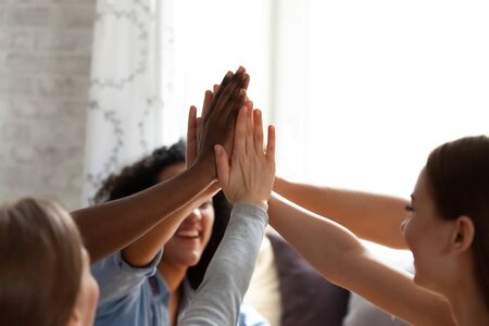 Close up mixed race group of happy smiling friends giving high five, multi ethnic friends bonding...