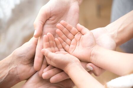 Close up of three caucasian person stack their palms. Grandmother mother and granddaughter holding...