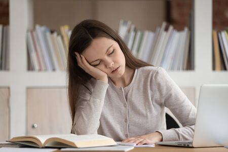 Tired girl fall asleep at workplace feeling fatigue preparing for final school exam or test,...