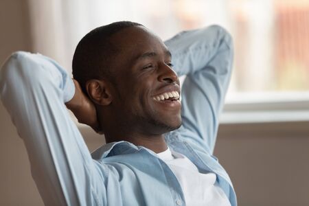 Close up image african guy student accomplish study put hands behind head feels satisfied resting contemplating sit indoors, taking break stress relief, successful good results, completed work conceptの写真素材