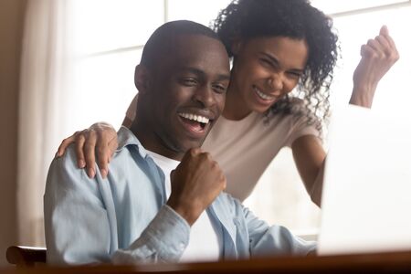 Black 30s couple look at pc screen feels excited celebrating lottery win results, unbelievable lucky moment happy opportunity, last loan payment or mortgage approval, succeed goal, great offer conceptの素材 [FY310127894137]