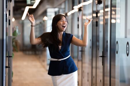 Excited funny young asian business woman celebrate success in victory dance, happy euphoric proud...