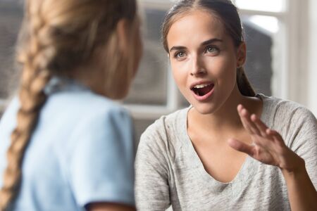 Focus on friendly teacher teach autistic child communicating with little deaf-mute girl using sign language gestures, young mother talking playing with daughter emotionally gesticulating concept imageの写真素材