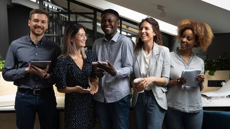 Cheerful happy multicultural business team people laughing joking having fun standing together in modern office, friendly positive multiracial colleagues employees good relations lifestyle communicationの写真素材