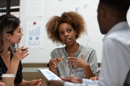 Serious female african leader manager talking during group office briefing teaching multiracial...