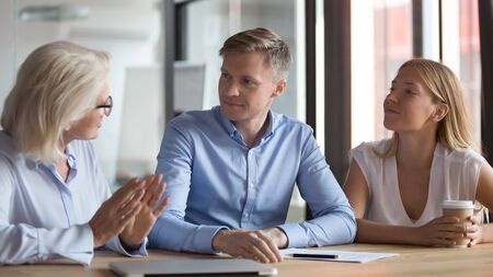 Young couple visit relator or broker office having consultation with female real estate agent, millennial husband and wife talk with woman counsellor or lawyer discussing future plan or purchaseの写真素材