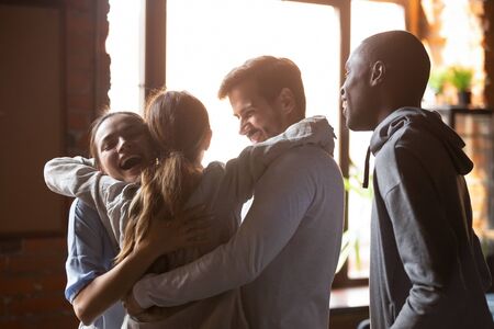 Happy diverse best friends embracing, greeting in cafe at sudden meeting, standing together, excited...