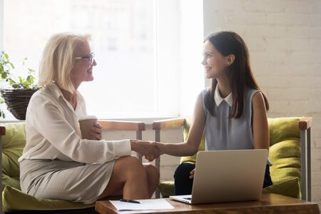 Happy female employee handshake get acquainted at office meeting, smiling woman business partners shake hands thanking for successful negotiations congratulating with deal close. Cooperation conceptの写真素材
