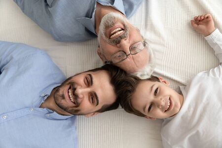 Happy intergenerational 3 three generation men family concept lying in circle close up portrait,...