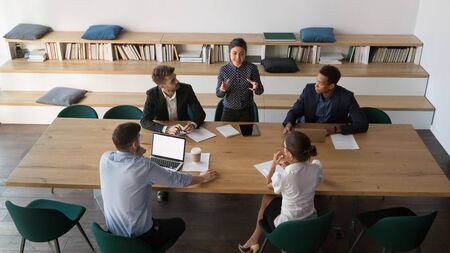 Indian leader manager talk to multiethnic employees team at diverse group meeting, female hindu...
