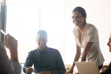 Smiling diverse office business team people talking gathered at conference table in modern...