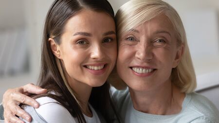 Head shot close up portrait of happy mature lady bonding with attractive grown up daughter. Smiling...