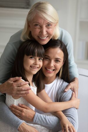 Vertical image happy middle aged woman cuddling smiling bonding grown up daughter and little...