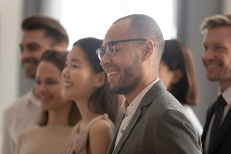 Diverse employees with African American leader wearing glasses posing for company photo close up, happy multiracial businesspeople showing unity, standing together, motivated for business successの写真素材