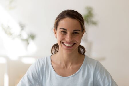 Head shot close up portrait overjoyed young mixed race woman posing fpr photo. Happy smiling sincere multiracial millennial lady looking at camera. Positive face expression, good mood concept.の写真素材