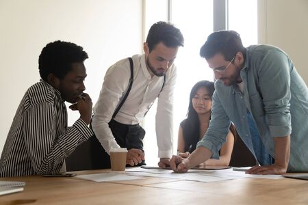 Diverse employees team analyzing project statistics, working with legal documents at meeting,...