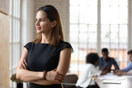 Head shot distracted from work dreamy young businesswoman standing with folded hands, looking at...