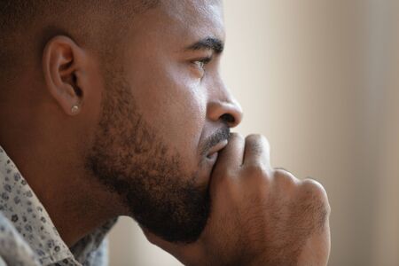 Close up side profile view of pensive upset african American man look in distance thinking of personal problems, thoughtful sad biracial male feel depressed lost in thoughts pondering, having dilemmaの写真素材