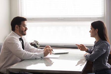 Male Caucasian broker or realtor meeting with millennial woman client talking about contract terms or closing deal, man counselor or banker consulting female customer considering cooperationの写真素材