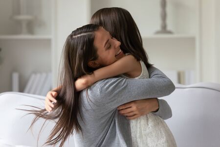 Happy mother strong cuddles her little daughter, mom snuggle kid girl showing unconditional love and protection, miss each other concept of single mother sole custody, new loving mum for adopted childの写真素材