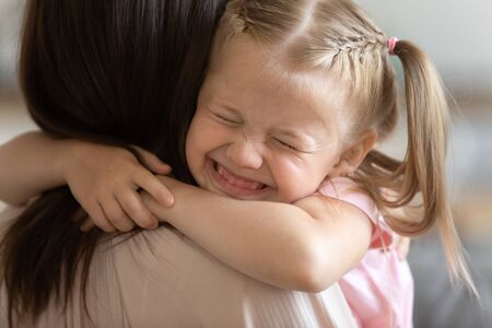 Funny little child girl smiling embrace foster care parent mum, adorable sweet small kid adopted daughter cute face hug mother caretaker holding tight feel happy express love get new family conceptの写真素材