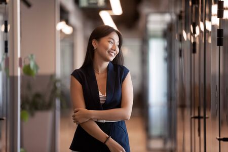 Attractive young asian ethnicity businesswoman standing in modern office hallway, career growth of...