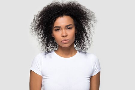 Dissatisfied millennial African American woman looking at camera, showing negative attitude, headshot portrait irritated young female wearing white t-shirt, isolated on studio backgroundの写真素材