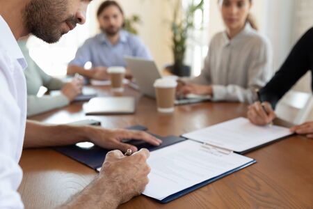 Cropped image two business partners signing agreement documentations after negotiations with lawyers and financial advisors at office. Successful businessmen making commercial deal at meeting.の写真素材