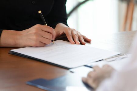 Close up cropped image young woman signing business agreement with partner after reading terms of...