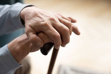 Close up view 60s lovely male hands holding cane. Parkinson disease, nursing home for elderly,...