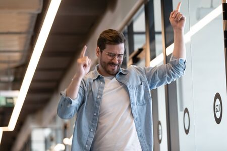 Funny happy millennial businessman celebrate business success or goal achievement, excited overjoyed male employee have friday fun perform winner dance, pleased with promotion, reward conceptの写真素材