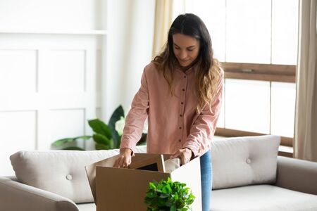 Millennial Caucasian wife unpack cardboard boxed moving to new house or apartment, excited young...