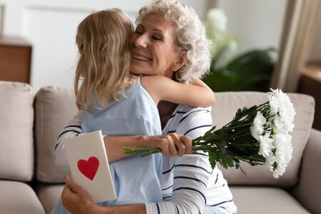 Head shot little child girl congratulating happy elderly senior granny with 8 March birthday at...