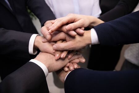 Close up diverse business people stacking hands together showing unity, professional support, good team work. Multiracial employees sharing corporate success, involved in team building activity.の写真素材