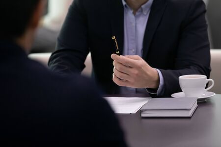 Close up solicitor lawyer real estate agent holding pen, ready signing contract with client, sitting together at table. Confident businessman offering putting signature to partnership agreement.の写真素材
