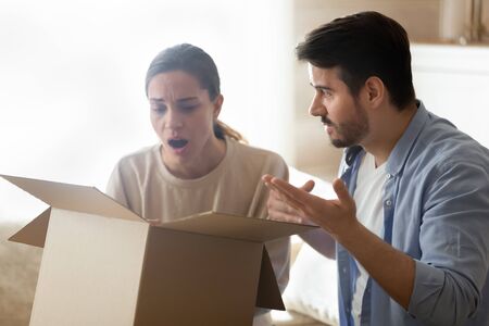 Disappointed man and woman unpack cardboard box shopping online frustrated by wrong bad quality...