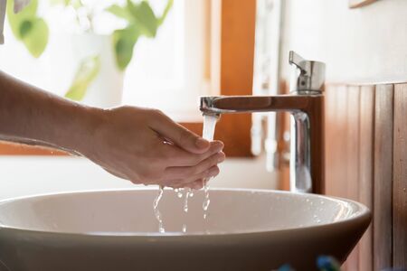 Caucasian man clean hands do face morning routine in clear tap running water from sink in home...