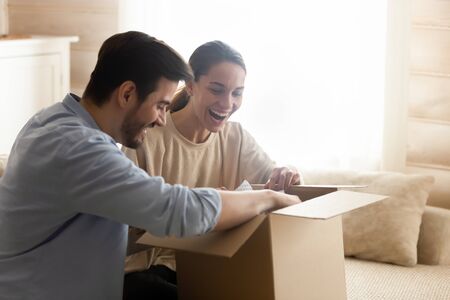 Overjoyed millennial couple feel euphoric open cardboard package buying goods shopping online...