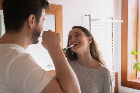 Overjoyed millennial loving couple enjoy daily morning routine in new renovated design bathroom,...