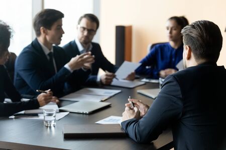 Close up businessman back sit at table in boardroom at company meeting. Confident employee listens...