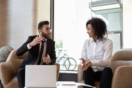 Middle eastern ethnicity businessman african businesswoman meet in modern office seated on armchairs discuss deal, share startup ideas, working together on common project, negotiations process conceptの写真素材