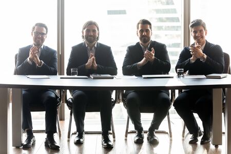 Happy businessmen with applicant resume clap hands for job seeker and congratulating. Smiling handsome man hr employer managers hiring new candidate making good first impression.の写真素材