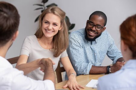Smiling businesswoman shaking hand of business partner at meeting in boardroom, diverse colleagues...