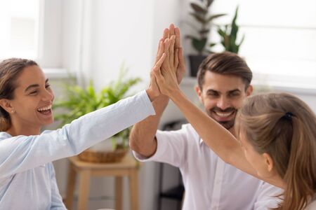 Close up excited employees giving high five after successful negotiations, team motivated for better...