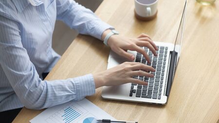 Close up businesswoman using laptop, writing financial report, analyzing project results, document...